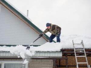 a technician removing snow from a roof on a home